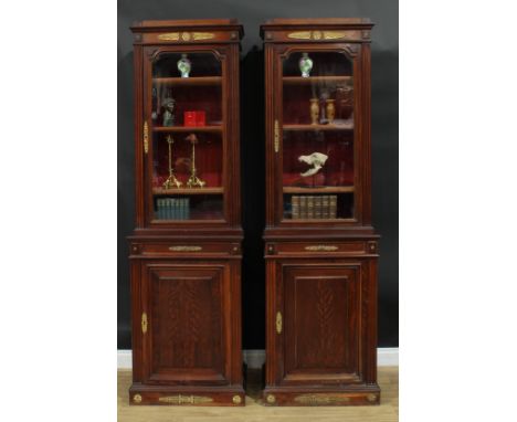 A pair of 19th century French Empire design gilt metal mounted mahogany pier bookcases, each with an outswept cornice above a