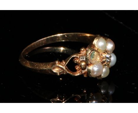A Victorian gold flower head mourning ring, set with a central old cut diamond surrounded by five seed pearls, openwork heart