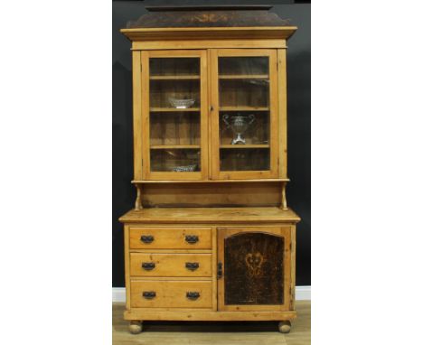 A Victorian pine dresser, outswept cornice with painted pediment above a pair of glazed doors enclosing three adjustable shel