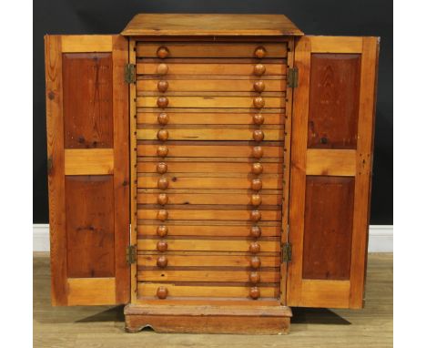 An early 20th century pine enclosed collector’s specimen chest, rectangular top above a pair of panel doors enclosing sixteen