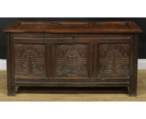 An 18th century oak blanket chest, hinged top enclosing a till above a three panel front carved with stylised leaves and flow