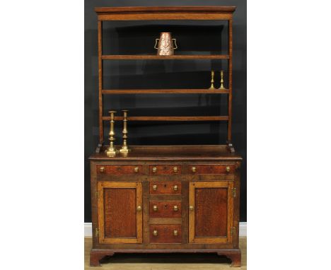 A George III oak dresser, moulded cornice above three plate racks, the projecting base with a mahogany crossbanded rectangula