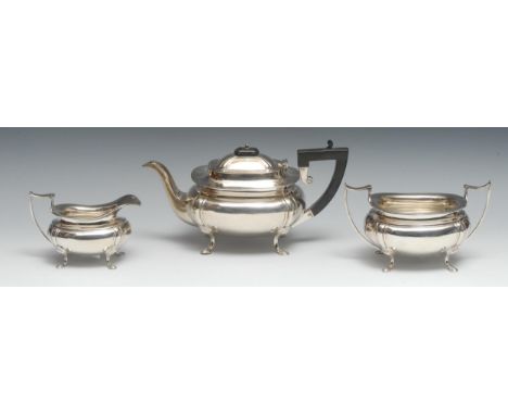 A George V silver three piece boat shaped tea service, comprising teapot, milk jug and sugar basin, fluted angles, pad feet, 