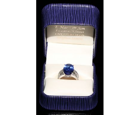An 18ct white gold diamond and tanzanite ring, 5.83ct central oval tanzanite, flanked by ten baguette (.99ct combined) and tw