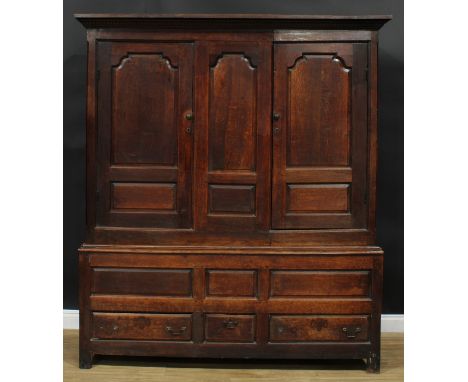 A George III oak housekeeper’s provision or livery press cupboard, outswept cornice above a pair of raised and fielded panel 