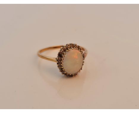 A hallmarked 9ct yellow gold opal and diamond cluster ring, set with an oval opal cabochon, measuring approx. 8x10mm, surroun