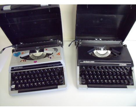 Silver Reed Leader and a silver Reed SR100 typewriter in original cases (2)