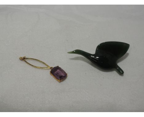 A yellow metal drop pendant with amethyst style stone, marks worn and a jade brooch modelled as a stylised flying goose