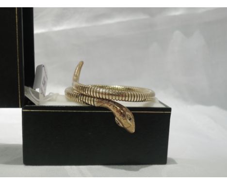 A 9ct gold snake bangle having ruby eyes and engraved decoration to head on coiled body with internal steel springCONDITION R
