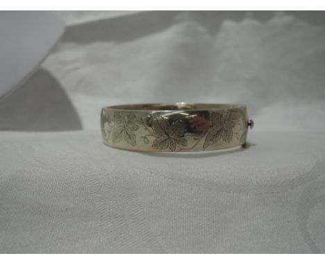 A silver hinged bangle having engraved ivy leaf decoration