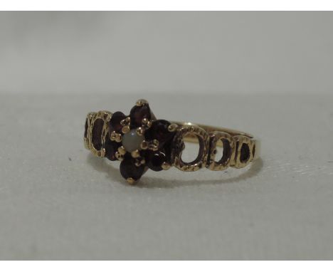 A lady's dress ring having a garnet and seed pearl cluster to bark effect link shoulders on a 9ct gold loop, size M