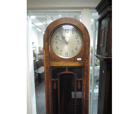 An early 20th century oak cased grandmother clock having arch top with circular silvered dial, over glass trunk and square ba