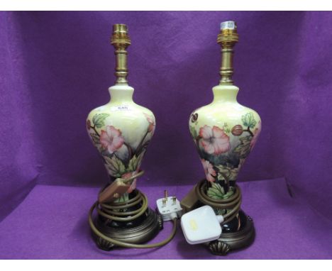 A pair of modern ceramic table lamps in the Moorcroft style having floral decoration on yellow ground