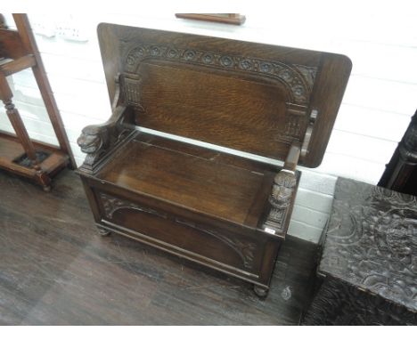A mid 20th century oak monks bench having carved fold over table top on lion supports and box base