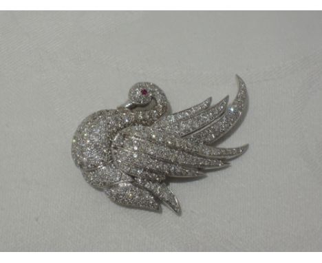 A white metal diamond encrusted brooch modelled as a swan with ruby set eye,  no marks but tested as 18ct gold