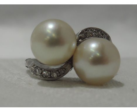 A lady's dress ring having a cultured pearl duo in collared mounts to diamond set crossover shoulders on a white metal patent
