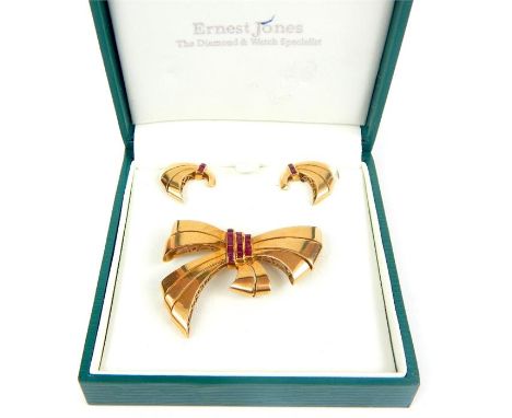 A vintage high carat yellow gold and ruby suite consisting of a stylised bow brooch and earrings all set with channel set squ