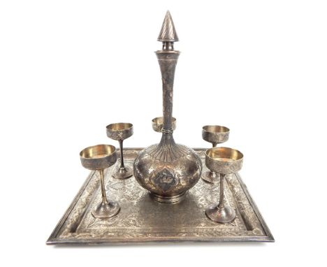 An antique handmade Persian silver decanter and five stemmed drinking cups on a silver tray. decorated with a proliferation o