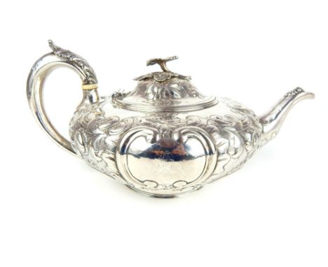 A Victorian silver teapot with repousse decoration of scrolling acanthus leaves, flowers and cartouches flanked by C-scrolls 