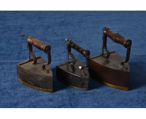 Three Wilkinson Box Irons, each having brass bases, one for E&T Clark, another for Fenwick, all with turned wooden handles an