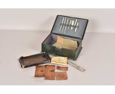 A small collection of Needlework Stencils, in copper, with a small collection of bone needlework tools and a white metal need