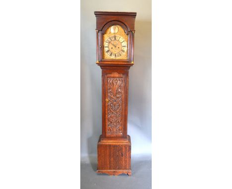 An Oak Long Case Clock, the arched hood with turned pilasters above a carved door raised upon low bracket feet, the brass dia