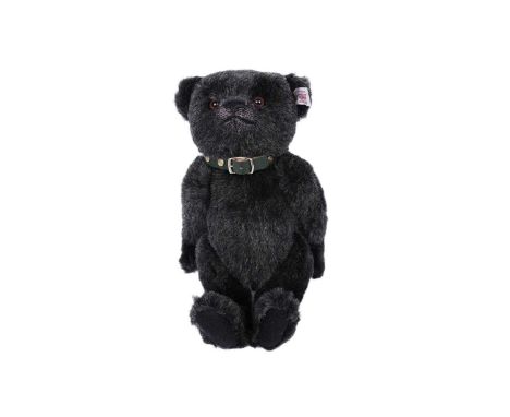 A Steiff bear, black plush with plastic eyes, button and label to ear, wearing green collar with Steiff studs, 27cms high.