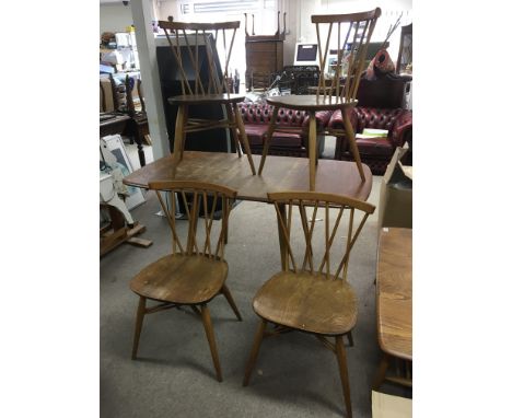 An Ercol light elm drop leaf table with flour conforming stick back chairs.Table approx 74x135 cm fully extended.