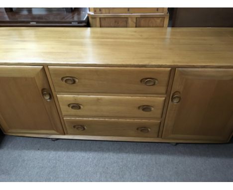 A Ercol sideboard with 3 drawers flanked by two cupboards