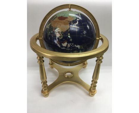 A terrestrial gemstone globe on a brass stand, compass missing.