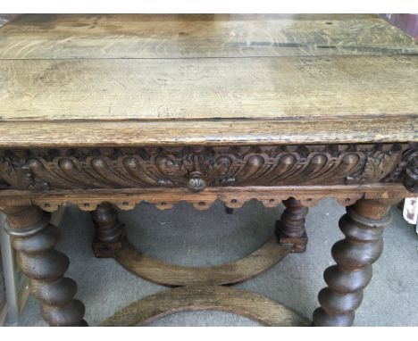 A oak carved desk with single drawer on barley twist legs united by stretchers