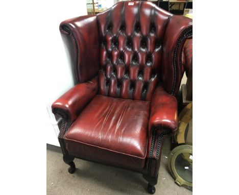 A Red leather button back wing arm chair on cabriol legs.