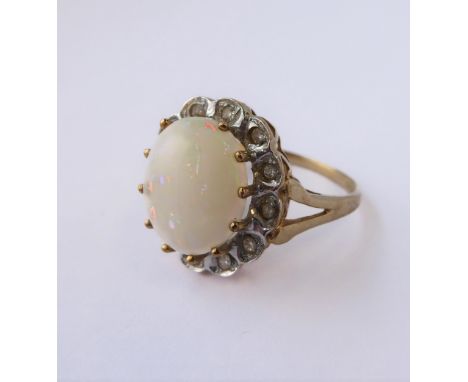 A 9-carat gold dress ring set with an opal surrounded by white gemstones (boxed)