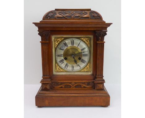 A late 19th century walnut-cased eight-day mantle clock: the domed top with Art Nouveau style carving above a silvered chapte