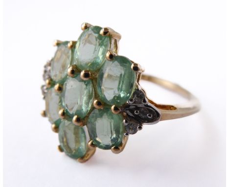 A lady's 9-carat gold dress ring (marked '375'): seven hand-cut light green stones in a flower-head design flanked by further