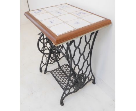 A tile-topped occasional table with a cast-iron treadle sewing machine base with decorative pierced ends (59 x 47 x 77.5 cm h