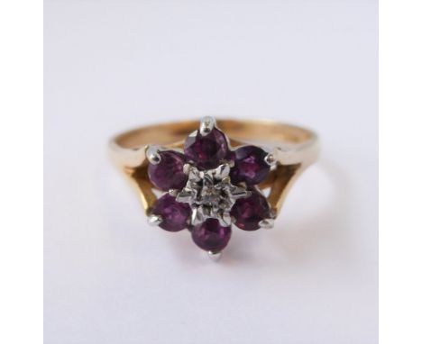 A lady's 9-carat yellow gold dress ring (marked '375'): flowerhead cluster with six cut stones (probably amethyst) within ope