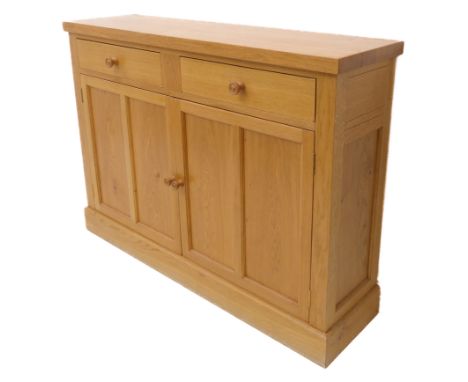 A modern light oak side cabinet; two half-width drawers above two panelled doors and raised on plinth base (110.5 x 30 x 80 c