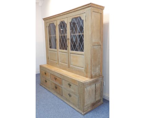 An early 20th century oak dresser of large proportions; outset cornice above three leaded-light glazed doors with fielded pan