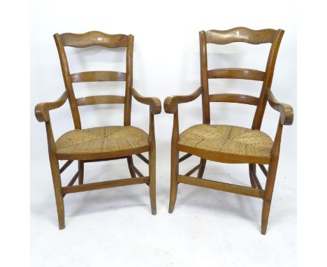 A pair of similar early 20th century rush-seated ladder-back elbow chairs 