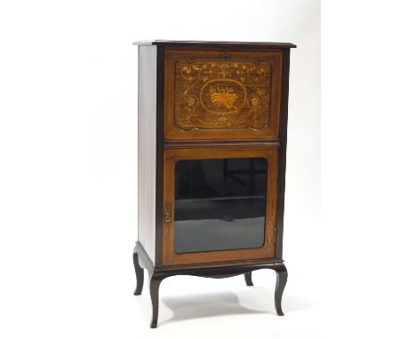 An Edwardian mahogany music cabinet, the fall front inlaid with scrolling foliage and musical motifs above a glazed cupboard 