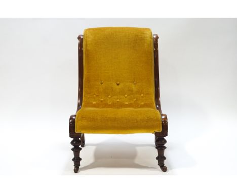 A Victorian mahogany button back nursing chair with scroll detail to frame, raised on turned front legs and upholstered in ye