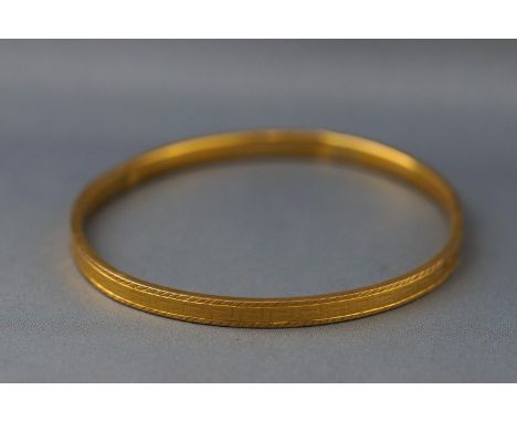 A yellow metal very large bangle with Greek Key design. Marks illegible but tests indicate 9ct gold. 9.2 grams