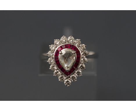 A white metal pear shaped diamond and ruby cluster ring. The rose cut central pear shape diamond is 0.27ct. Diamond cluster s