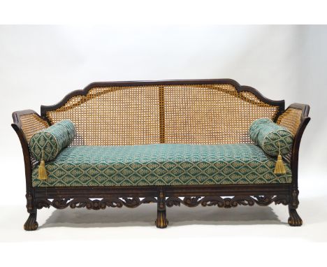 A carved, shaped, mahogany Bergere sofa raised on sabot feet on a carved front rail 82 x 174 x 79 cms