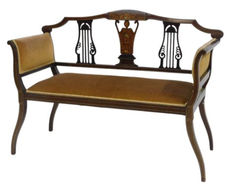 An Edwardian mahogany and marquetry salon sofa, the pierced back with cherub and instrument inlaid back, overstuffed seat and