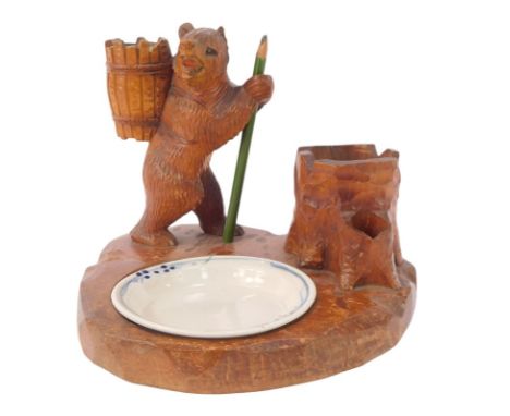 A Black Forest style desk stand, modelled as a bear wearing a barrelled rucksack beside a tree stump with porcelain inkwell w