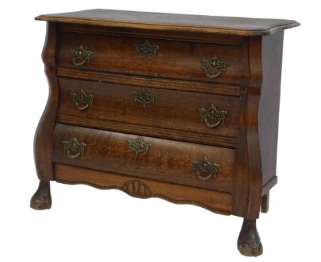 A 20thC oak bombe commode, the top with moulded edge above three drawers, on ball and claw feet, 63cm high, 70cm wide, 34cm d