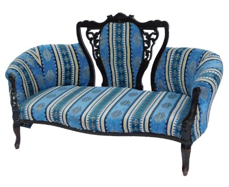 A Victorian ebonised sofa, the scroll and leaf pierced carved back inset with a striped and patterned upholstered panel, over