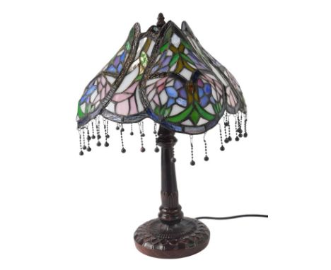 A Tiffany style table lamp, the leaded glass shade decorated with abstract flowers, in purples, pinks and greens, the shade w